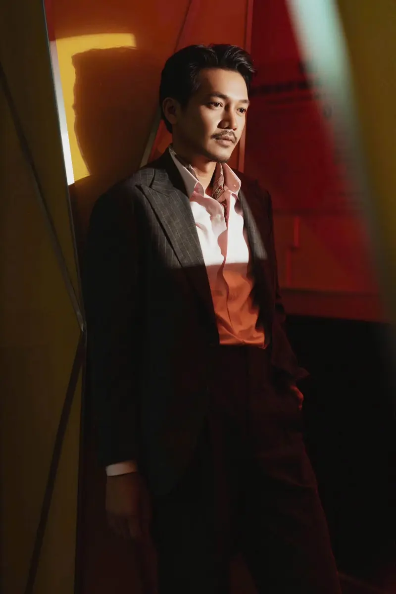Close portrait of Quang Tuấn in a pinstripe jacket and open-collar shirt