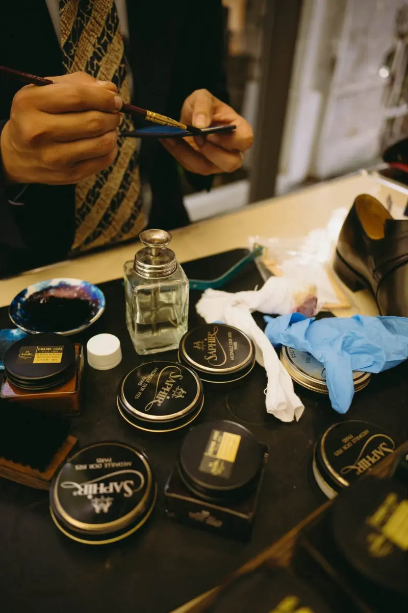 Shoe-care tins, brushes and polish laid out on a table at the trunk show