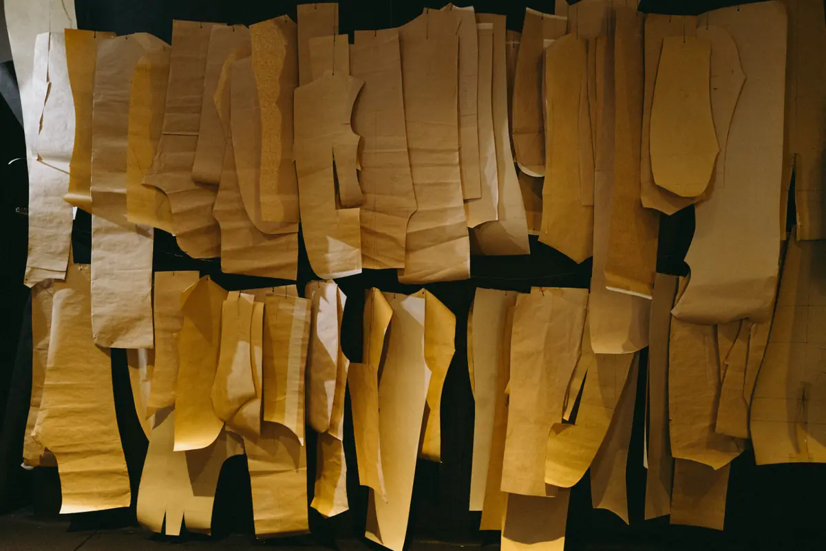 Brown paper pattern pieces hanging in rows in the atelier